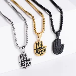 Tre ciondoli Hamsa Om in acciaio inossidabile argento, oro e nero su sfondo bianco