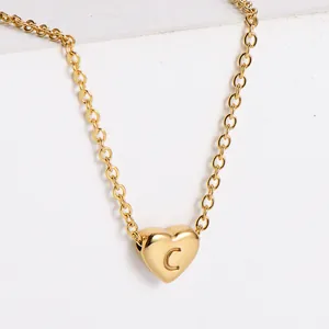 Macro shot of gold heart pendant with engraved letter C on minimalist chain necklace