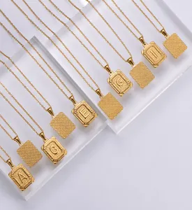 Detail of 18k gold plated rectangle letter pendants with diamond cut texture on chain
