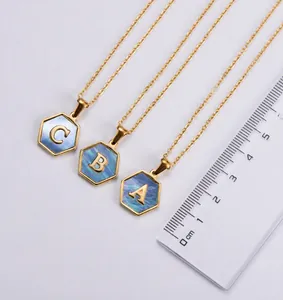 Dettaglio macro di ciondoli esagonali placcati oro 18k con intarsio in blu e lettere A B C
