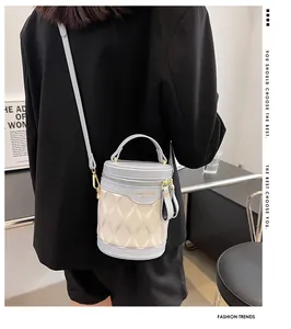Detail of color-block cylindrical bucket bag with quilted texture and gold logo