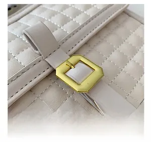 Gros plan d'un sac en similicuir matelassé beige avec boucle métallique dorée élégante