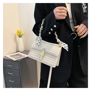 Détail du sac à bandoulière matelassé blanc avec chaîne dorée et foulard à pois