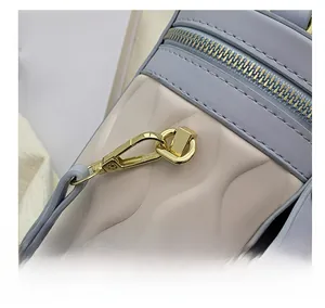 Close-up of golden hardware hooks and wavy quilted texture on a two-tone bucket bag