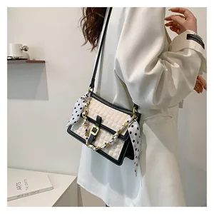 Détail du sac bandoulière matelassé avec chaîne dorée, couleurs contrastées et accessoire foulard