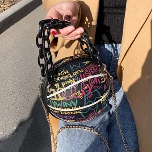 Detail of basketball shaped purse featuring colorful graffiti and double chain straps