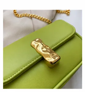 Dettaglio borsa baguette verde neon con fibbia metallica dorata e tracolla a catena