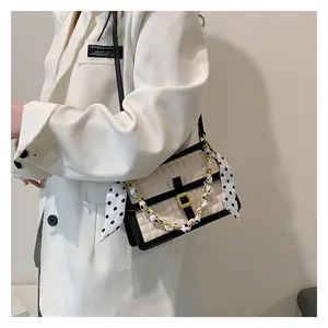 Détail du sac à main matelassé avec foulard à pois sur la chaîne et blazer blanc