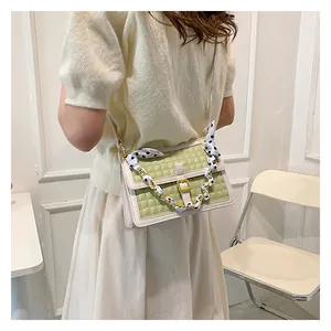 Détail du sac bandoulière matelassé vert clair avec fermoir doré et foulard à pois