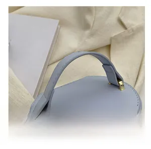 Close-up of a blue leather handbag showing the round handle and gold hardware detail