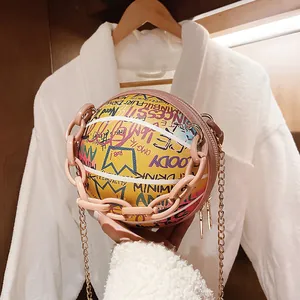 Close-up of a basketball-shaped crossbody bag with colorful graffiti and pink chain handle