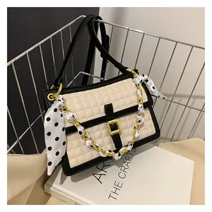Détail du sac bandoulière matelassé avec chaîne dorée et foulard en soie à pois