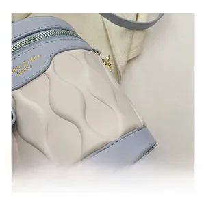 Detail of blue and white bucket bag featuring wavy texture and gold metal zipper hardware