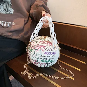 Detail of round graffiti basketball bag with chunky white chain and gold strap