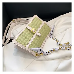 Détail du sac bandoulière matelassé vert avec chaîne et foulard en soie à pois