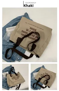 Detail van de kaki canvas tote bag met donkerbruine hengsels en tekstontwerp