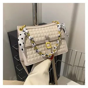Détail du sac matelassé crème avec bandoulière chaîne dorée et foulard à pois noué