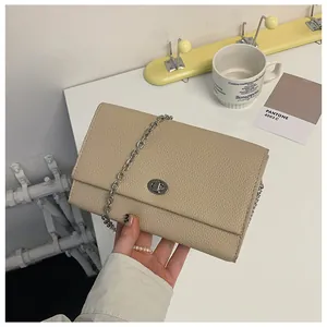 Dettaglio della borsa a catena in pelle beige con chiusura rotante in metallo argento