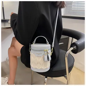 Blue and beige patchwork bucket bag with rhombus embossing held by model in black suit