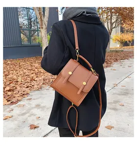 Detail van vintage bruine PU-lederen crossbodytas met gespbanden op een herfstjas