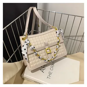 Détail du sac à main matelassé crème avec boucle dorée et anse ornée d'un foulard à pois