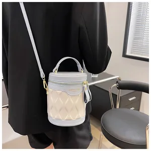 Detail of a color-block bucket bag with wavy texture and gold hardware on black suit