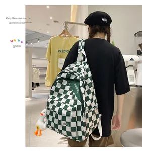 Zaino in tela a scacchi verdi con ciondolo a forma di papera indossato da modella
