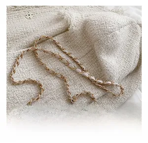 Detail shot of golden metal chain strap and white quilted faux leather material