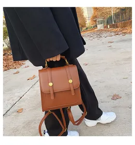 Close-up of a vintage brown PU leather backpack with gold metal hardware and top handle