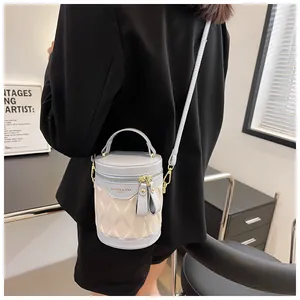 Detail of a cream quilted bucket bag with light blue accents worn with a black suit jacket