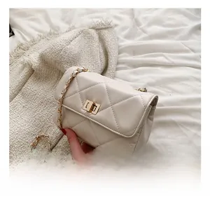 Close-up of beige quilted crossbody bag with gold twist lock and metal chain strap
