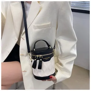 Detail of the black and white quilted cylinder bag with gold zippers and metal strap hooks