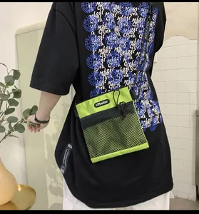 Detail of neon green nylon crossbody bag with black mesh pocket on casual outfit