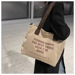 Zijaanzicht van de beige canvas shopper met bruine tekst en brede schouderband
