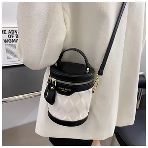 Detail of a black and white cylinder bucket bag with a wave texture and golden logo