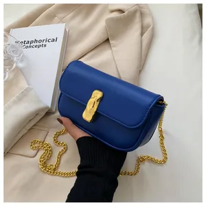 Dettaglio della borsa in pelle blu reale con chiusura geometrica oro e tracolla a catena
