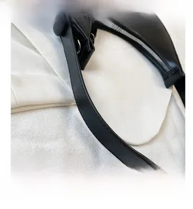 Detail of black leather half-moon bag featuring silver zipper and precise stitching