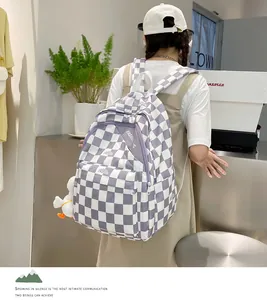 Dettaglio dello zaino a scacchi viola con etichetta fashion e ciondolo a forma di papera