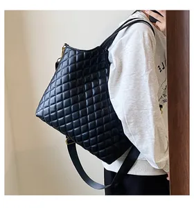 Detail of black quilted tote bag with golden hardware and wide nylon shoulder strap