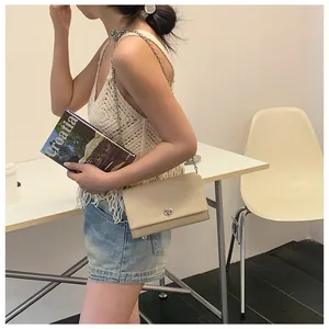 Dettaglio borsa a tracolla beige in pelle con catena d'argento e chiusura a rotazione