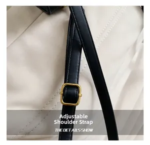 Detail of adjustable black leather strap with gold square buckle on white quilted bag