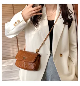 Close-up of brown quilted chain crossbody bag with golden turn-lock closure on a model
