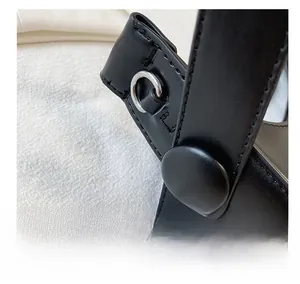 Macro detail of black leather crescent bag showing silver metal D-ring and fine stitching