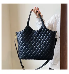 Macro shot of black quilted tote bag texture with gold hardware and shoulder strap details