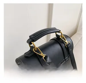 Detail of the black leather handbag showing top handle and premium gold metal hardware