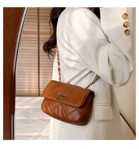 Detail of brown quilted leather crossbody bag with gold chain strap and metal turn-lock