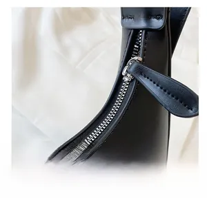 Close-up of premium stitching and silver metal zipper on a black leather handbag