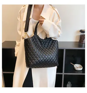 Quilted black leather tote bag with round handles and detachable wide strap on model