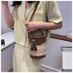 Detail of a two-tone cylindrical bucket bag featuring wave texture and brown leather trim