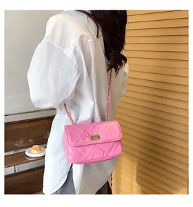 Detail of a pink quilted crossbody bag with gold chain strap on a wooden cafe table